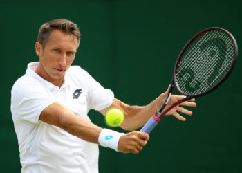 El ex tenista Sergiy Stakhovsky golpea un golpe de derecha con una pelota de tenis en movimiento.