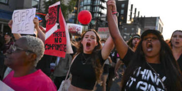 Los manifestantes se toman de la mano y gritan consignas mientras caminan por la calle U durante una protesta. "Poner fin a la ocupación de DC" Manifestación contra el presidente estadounidense Donald Trump y su uso de poderes de emergencia para hacerse cargo de la policía de D.C. en Washington, DC, el 23 de agosto de 2025.