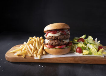 Hamburguesa doble vegana con queso sobre una tabla de madera.