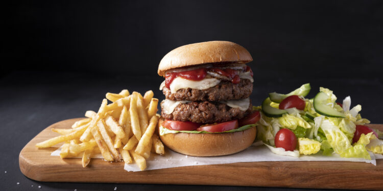 Hamburguesa doble vegana con queso sobre una tabla de madera.
