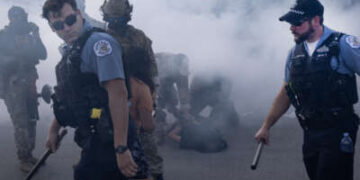 Oficiales de policía de Chicago y agentes federales encargados de hacer cumplir la ley se encuentran en una nube de gas lacrimógeno desplegado por agentes federales contra manifestantes en Broadview, Illinois, el 4 de octubre de 2025. La protesta estalló después de que un agente de Aduanas y Protección Fronteriza disparó a un manifestante anti-ICE en Brighton Park.