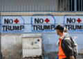 Una pareja pasa junto a un graffiti contra el presidente estadounidense Donald Trump el 26 de marzo de 2020 en Caracas, Venezuela.