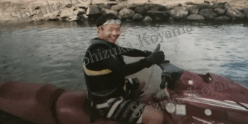 Takashi Yoyama sonriendo y levantando el pulgar mientras está sentado en una moto acuática.