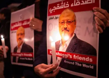 Personas sostienen carteles que muestran al periodista saudí Jamal Khashoggi y velas encendidas durante una reunión frente al consulado de Arabia Saudita en Estambul, el 25 de octubre de 2018. (Yasin Akgul/AFP vía Getty Images)