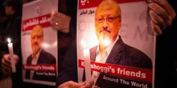 Personas sostienen carteles que muestran al periodista saudí Jamal Khashoggi y velas encendidas durante una reunión frente al consulado de Arabia Saudita en Estambul, el 25 de octubre de 2018. (Yasin Akgul/AFP vía Getty Images)