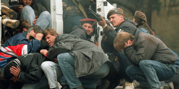 Soldados armados con rifles vigilan a los civiles atemorizados.