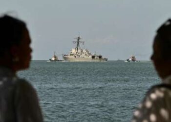 La gente observa al USS Gravely, un buque de guerra de la Armada de los EE. UU., que sale de Puerto España el 30 de octubre de 2025. El buque de guerra llegó a Trinidad y Tobago el 26 de octubre de 2025 para realizar ejercicios conjuntos cerca de la costa de Venezuela.