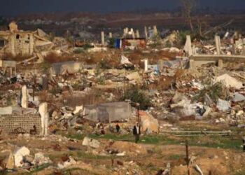 Un hombre camina junto a casas y edificios destruidos por el ejército israelí en el campo de refugiados de Nuseirat, en el centro de la Franja de Gaza, el 13 de diciembre de 2025. Las fuertes lluvias han inundado tiendas de campaña y refugios temporales en toda Gaza, agravando el sufrimiento de los residentes del territorio, casi todos los cuales fueron desplazados durante más de dos años de guerra.
