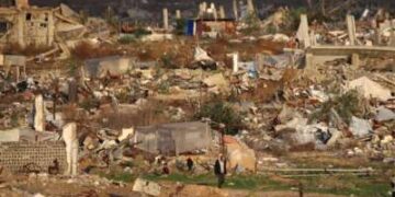 Un hombre camina junto a casas y edificios destruidos por el ejército israelí en el campo de refugiados de Nuseirat, en el centro de la Franja de Gaza, el 13 de diciembre de 2025. Las fuertes lluvias han inundado tiendas de campaña y refugios temporales en toda Gaza, agravando el sufrimiento de los residentes del territorio, casi todos los cuales fueron desplazados durante más de dos años de guerra.