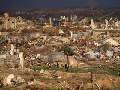 Un hombre camina junto a casas y edificios destruidos por el ejército israelí en el campo de refugiados de Nuseirat, en el centro de la Franja de Gaza, el 13 de diciembre de 2025. Las fuertes lluvias han inundado tiendas de campaña y refugios temporales en toda Gaza, agravando el sufrimiento de los residentes del territorio, casi todos los cuales fueron desplazados durante más de dos años de guerra.