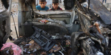 Niños palestinos desplazados miran un vehículo destruido por el ejército israelí, en la ciudad de Gaza, el 22 de noviembre de 2025.