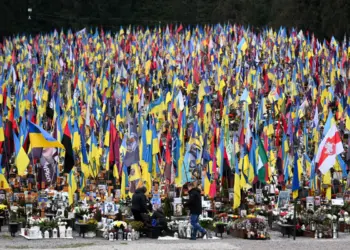 La gente llora ante las tumbas de militares ucranianos en el cementerio de Lychakiv el Día de las Fuerzas Armadas de Ucrania, en Lviv, el 6 de diciembre de 2025. (Yuriy Dyachyshyn/AFP vía Getty Images)