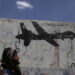 Un hombre yemení mira los graffitis que protestan contra los ataques con aviones no tripulados estadounidenses el 19 de septiembre de 2018 en Saná, Yemen.