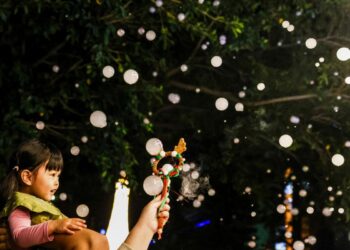 Un niño disfruta de una nevada artificial en una calle decorada con luces antes del festival de Navidad en Pingtung el 22 de diciembre de 2025. (I-Hwa Cheng/AFP vía Getty Images)