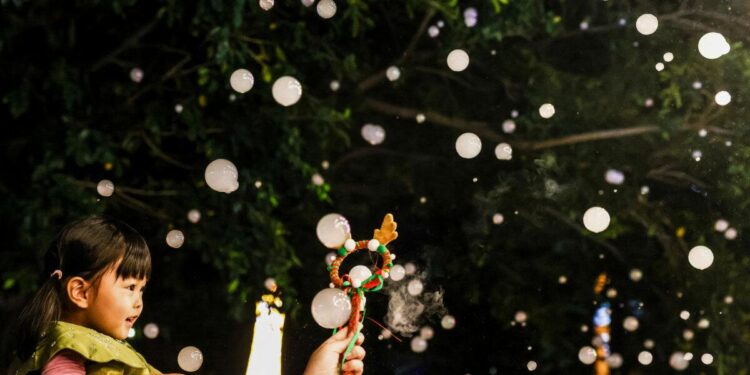 Un niño disfruta de una nevada artificial en una calle decorada con luces antes del festival de Navidad en Pingtung el 22 de diciembre de 2025. (I-Hwa Cheng/AFP vía Getty Images)