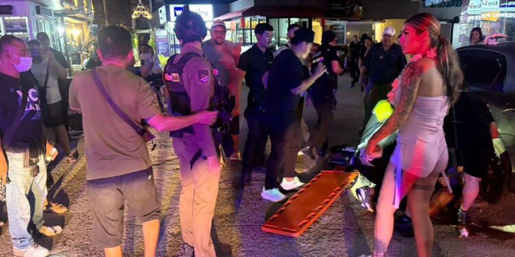 Un collage de imágenes que contiene 1 imagen. La imagen 1 muestra que los paramédicos y la policía atienden a una víctima en una calle por la noche.