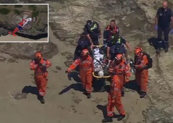 Un collage de imágenes que contiene 2 imágenes. La imagen 1 muestra al personal de emergencia llevando a una mujer herida en una camilla sobre un terreno rocoso. La imagen 2 muestra una vista aérea de un helicóptero rojo y blanco sobre una playa de arena y un acantilado rocoso.