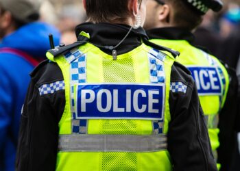 3 policías con chalecos amarillos mirando la pantalla grande