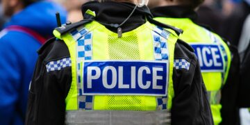 3 policías con chalecos amarillos mirando la pantalla grande