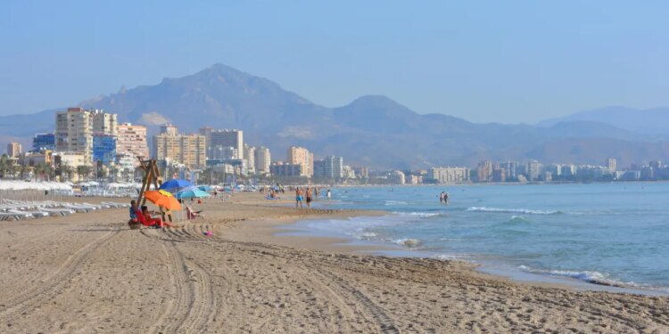 Mirando a lo largo de la playa de San Juan Playa hacia Campello, temprano en la mañana. Alicante, España