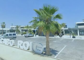 Un collage de imágenes que contiene 1 imágenes. La imagen 1 muestra Orihuela Costa, Alicante, España, con una zona comercial, palmeras, automóviles en un estacionamiento y letras blancas grandes. "CABO ROIG" en el suelo