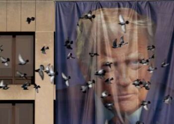 Los pájaros pasan volando junto a una pancarta gigante con la imagen del presidente Donald Trump colgada en el exterior del Departamento de Trabajo de EE. UU. el 5 de enero de 2026 en Washington, DC.