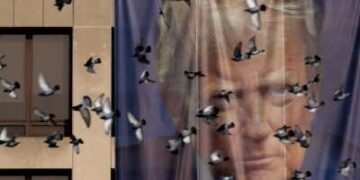 Los pájaros pasan volando junto a una pancarta gigante con la imagen del presidente Donald Trump colgada en el exterior del Departamento de Trabajo de EE. UU. el 5 de enero de 2026 en Washington, DC.