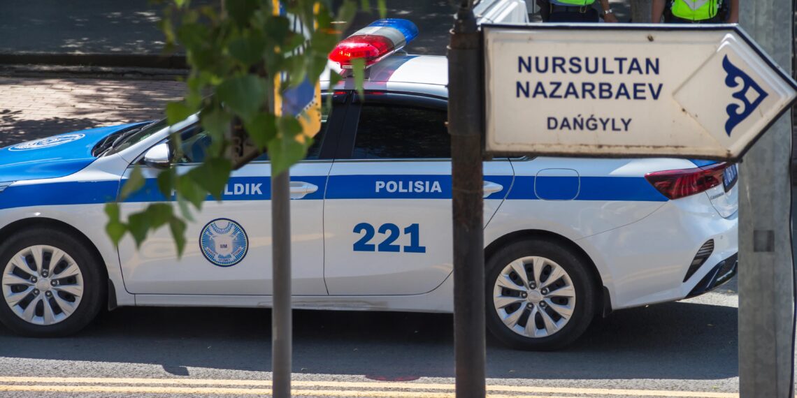 Coche de policía de Kazajstán en la avenida Nazarbayev. Cartel de la calle Nursultan Nazarbayev Avenue y una patrulla de policía detrás.