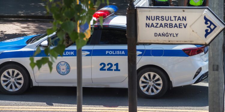 Coche de policía de Kazajstán en la avenida Nazarbayev. Cartel de la calle Nursultan Nazarbayev Avenue y una patrulla de policía detrás.