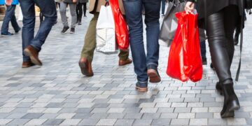 Personas con bolsas de compras caminan por la zona peatonal.