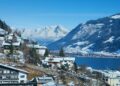 Un collage de imágenes que contiene 1 imágenes. La imagen 1 muestra una vista panorámica de Zell am See, Austria, con montañas cubiertas de nieve, un lago y edificios en primer plano.