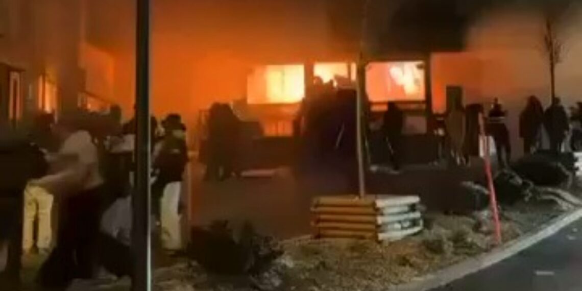 Edificio envuelto en llamas, del que sale humo.