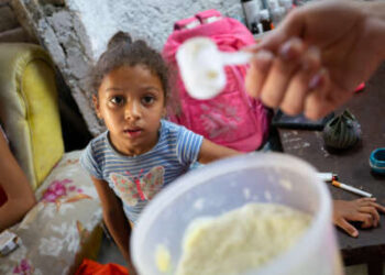 Una niña de 4 años observa la leche en polvo que recibe su madre a través del sistema de racionamiento cubano