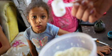 Una niña de 4 años observa la leche en polvo que recibe su madre a través del sistema de racionamiento cubano