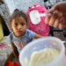 Una niña de 4 años observa la leche en polvo que recibe su madre a través del sistema de racionamiento cubano
