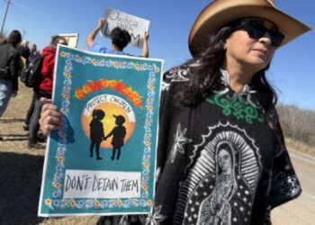 Un manifestante sostiene un cartel que dice "Proteja a los niños/No los detenga" mientras la gente se reúne durante una manifestación y vigilia frente al Centro Residencial Familiar del Sur de Texas en Dilley, Texas, el 28 de enero de 2026.