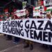 La gente marcha detrás de una pancarta que dice "DEJEN DE BOMBARDEAR GAZA; DEJEN DE BOMBARDEAR YEMEN" durante una protesta al aire libre