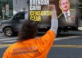 Activistas se reúnen mientras se ve un camión con vallas publicitarias móviles que acusa al presidente de la FCC, Brendan Carr, de censura, afuera de la sede de la FCC en Washington, DC, el 26 de marzo de 2026.