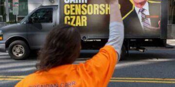 Activistas se reúnen mientras se ve un camión con vallas publicitarias móviles que acusa al presidente de la FCC, Brendan Carr, de censura, afuera de la sede de la FCC en Washington, DC, el 26 de marzo de 2026.