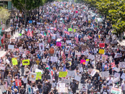 Personas ondeando banderas y portando carteles llenan una calle durante la protesta No Kings