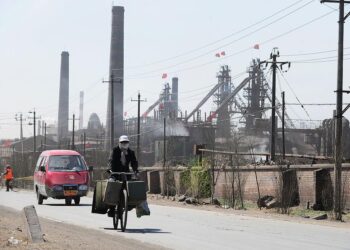 Un ciclista recorre una carretera polvorienta con docenas de fábricas que procesan tierras raras, hierro y carbón, en las afueras de la ciudad de Baotou en Mongolia Interior, noroeste de China, el 21 de abril de 2011. (Frederic J. Brown/AFP/Getty Images)