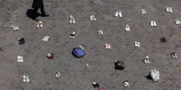 Una mujer iraní pasa junto a pertenencias simbólicas colocadas en el suelo en la plaza Valiasr de Teherán el 24 de abril de 2026, en homenaje a las colegialas de Minab que murieron en un ataque aéreo.