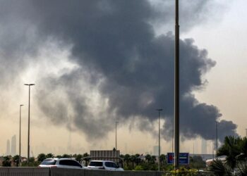 El horizonte de Dubai con el emblemático rascacielos Burj Khalifa se muestra como una columna de humo que se eleva desde un incendio en curso cerca del Aeropuerto Internacional de Dubai, Emiratos Árabes Unidos, el 16 de marzo de 2026. (Foto de AFP a través de Getty Images)
