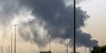 El horizonte de Dubai con el emblemático rascacielos Burj Khalifa se muestra como una columna de humo que se eleva desde un incendio en curso cerca del Aeropuerto Internacional de Dubai, Emiratos Árabes Unidos, el 16 de marzo de 2026. (Foto de AFP a través de Getty Images)