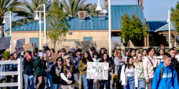 Los estudiantes realizan una huelga de la escuela mientras marchan detrás de una pancarta que dice "SÓLO PORQUE LA VERDAD DUELE NO SIGNIFICA DEJAR DE ENSEÑARLA"