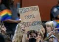 Una persona sostiene un cartel en oposición a una política que requeriría que el personal de la escuela "afuera" estudiantes a sus padres si solicitan ser identificados por un género que no figura en su certificado de nacimiento el 20 de julio de 2023 en Chino, California.