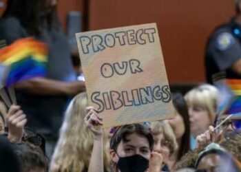 Una persona sostiene un cartel en oposición a una política que requeriría que el personal de la escuela "afuera" estudiantes a sus padres si solicitan ser identificados por un género que no figura en su certificado de nacimiento el 20 de julio de 2023 en Chino, California.